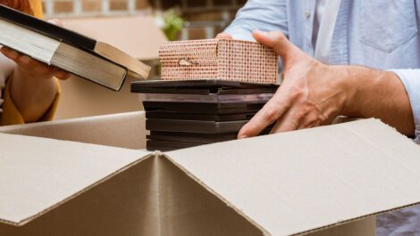 Person unloading a stack of DVDs out of a moving box.