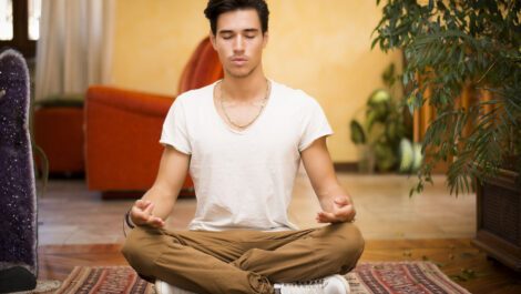 A young man meditates on his floor in his feng shui home.