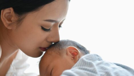 Young mother kissing her newborn baby's head.