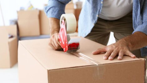 A man taping a moving box.