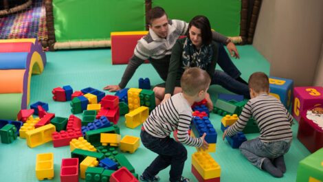 A young family playing with giant lego pieces.