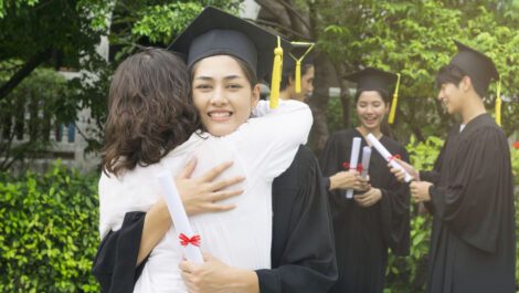 Parent hugging child after graduating from college.