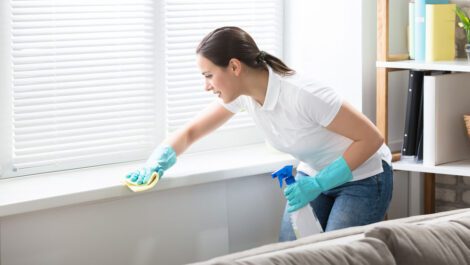 A woman dusting a windowsill.