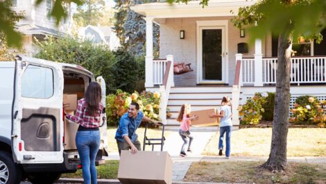 A family moving with children happily unloads boxes into their new home.