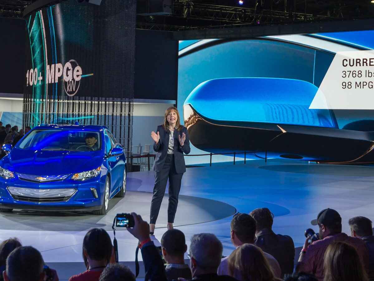 A vehicle showcased at the NAIS and a woman presenting to a crowd.