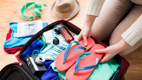 Woman packing a suitcase for a beach vacation.
