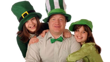 A man and two children wearing St. Patrick's Day accessories.