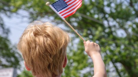 Young boy waving a small American flag in his hands.