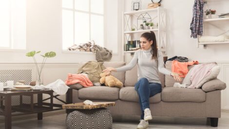 A stressed out woman looking at the mess on her floor.