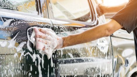 Person washing a black car with soap.