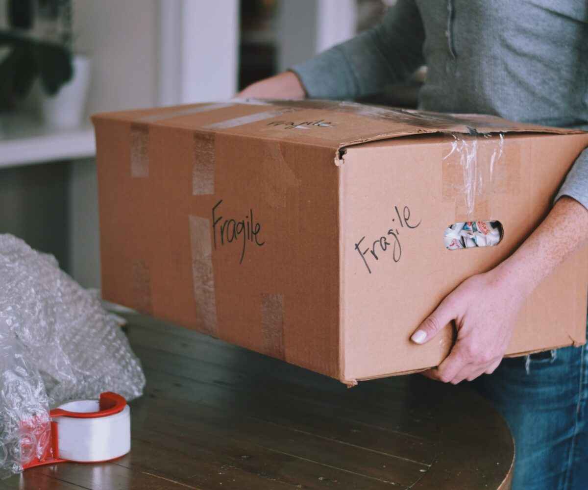 Man carrying a fragile box into a house.
