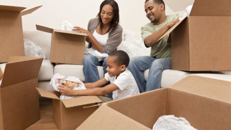 Family of three unpacking moving boxes.