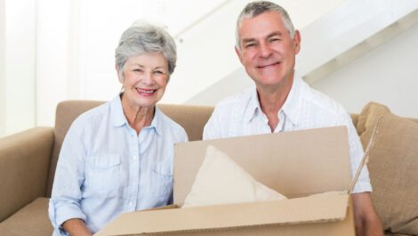 Cheerful elderly couple holding a moving box.