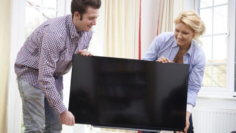 Young couple moving a television.