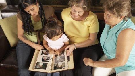 Three woman and a child looking at a family photo album.