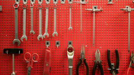 Handtools hanging on a red peg board.