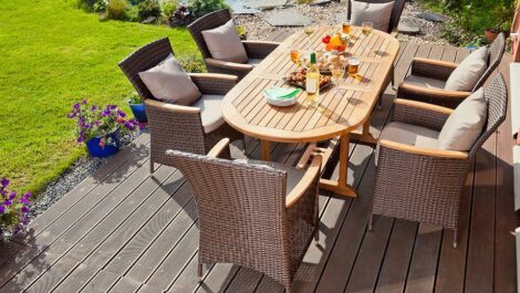 Patio table with food and drinks on it in a backyard.