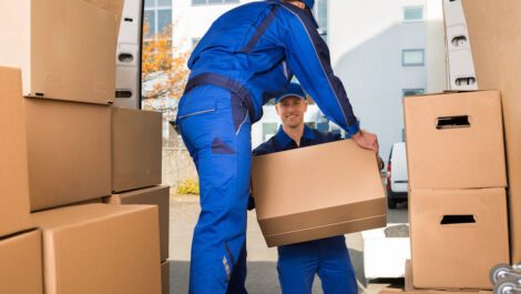 Two men moving boxes out of a moving van.