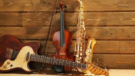 Guitar, violin, and saxophone leaning against a wall.
