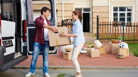 Man passing a moving box to woman from a van.
