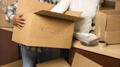 Middle aged couple unloading kitchen supplies from moving boxes.