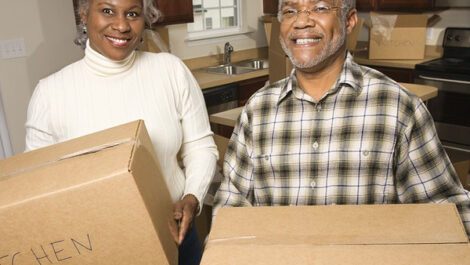 Middle aged couple carrying moving boxes.