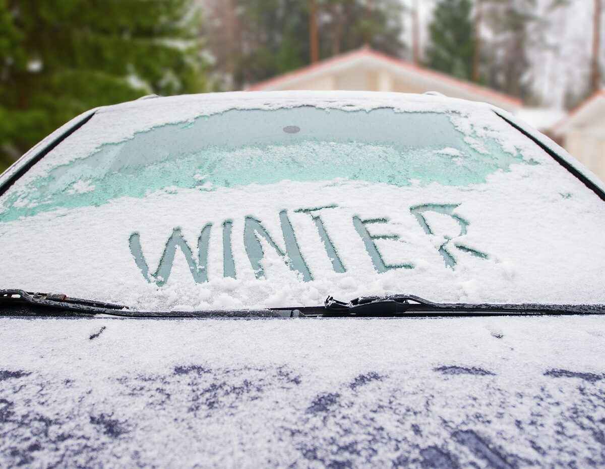 Car covered in snow with winter written on the windshield.