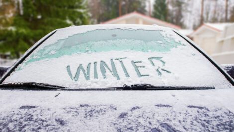 Car covered in snow with winter written on the windshield.