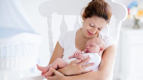 Young mother holding her sleeping newborn baby.