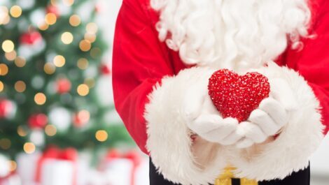 Santa Clause holding a red heart.
