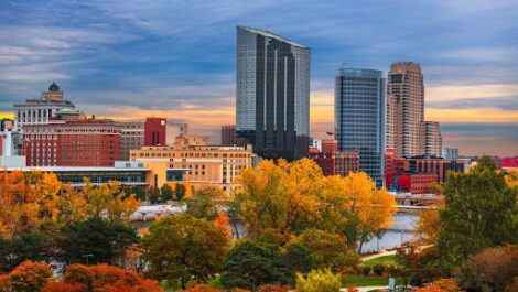 The Grand Rapids, MI, skyline in the fall, dotted with trees that have green, orange, and red leaves.