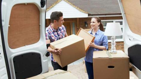 Young couples moving boxes into a van.