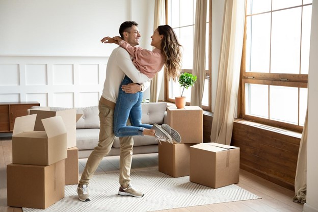 A man and woman dancing among moving boxes.